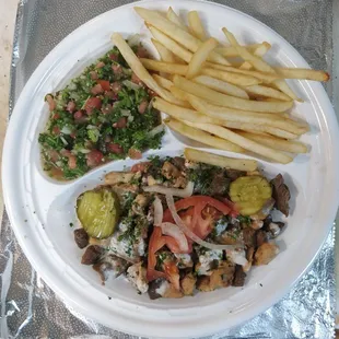 Opened shawarma with beef and chicken with sides of french fries and Taboule salad.