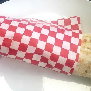 a burrito wrapped in red and white checkered paper