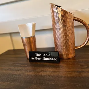 a copper pitcher and a glass on a table