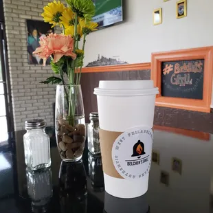 a cup of coffee and a vase of flowers