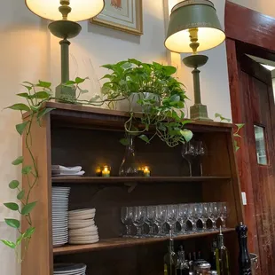 a dining room with a buffet, wine glasses, plates, and a potted plant