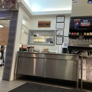 Interior view toward kitchen, drink machines, and sanitation score.