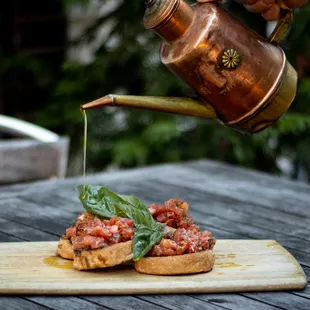 a person pouring olive oil onto a piece of bread