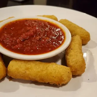 a white plate with a bowl of tomato sauce