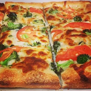 a close up of a pizza with tomatoes and broccoli
