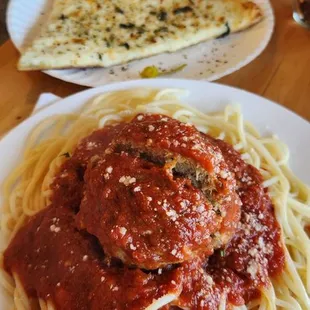 Generous children&apos;s serving of spaghetti and big meatball. White pizza slice, incredible crust.