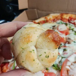 a hand holding a piece of pizza