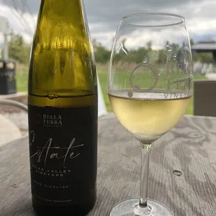 a glass of white wine next to a bottle of wine