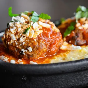 two meatballs covered in sauce and garnished with parsley
