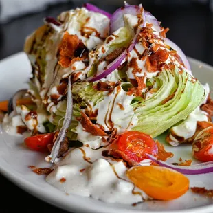 a wedge of lettuce with dressing and tomatoes