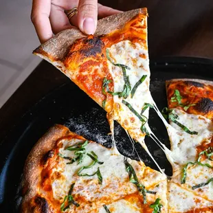 a person taking a slice of pizza