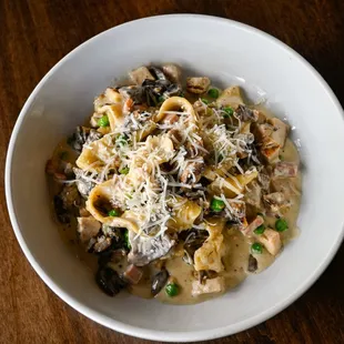 a bowl of pasta with peas, mushrooms, and parmesan cheese