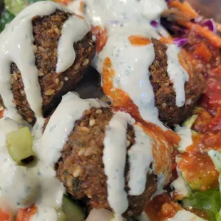 Falafel salad bowl: 3 big falafels over greens and house made fresh tzatziki sauce, tossed with cucumber tomato salad and rainbow slaw