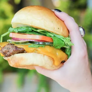 a hand holding a cheeseburger