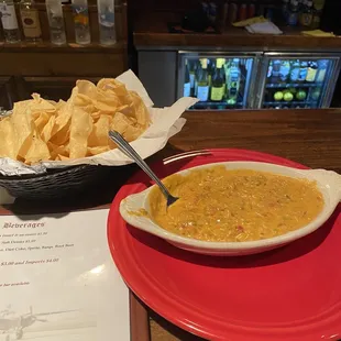 a bowl of soup and chips on a red plate