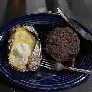 a steak and baked potato on a blue plate