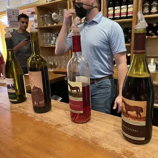 a man standing behind a bar with bottles of wine