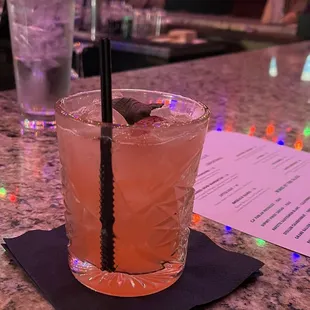 a pink drink with a black straw