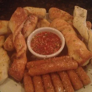a plate of breadsticks and dipping sauce