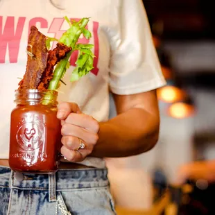 a woman holding a jar of bacon and celery