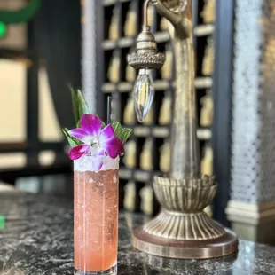 a pink cocktail with a purple flower garnish