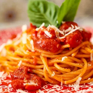 a plate of spaghetti with tomato sauce and basil leaves