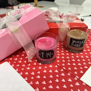 a pink gift box, two candles, and a candle
