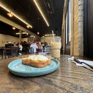 Avocado toast in a blue plate and an iced oat milk latte.