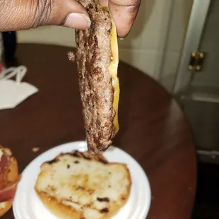 a hand holding a sausage sandwich