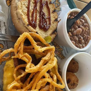 Cowboy - beef patty with cheddar cheese, bacon, pickled jalapenos, BBQ sauce, fried onion strings on a wheat bun.  Pinto Beans. Hushpuppies