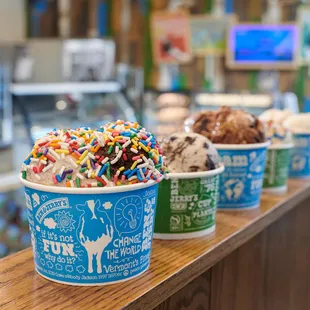 Multiple ice cream cups on a railing in a Ben &amp; Jerry&apos;s ice cream shop.