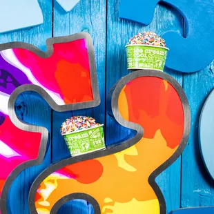 Two cups of ice cream with sprinkles on Ben &amp; Jerry&apos;s Logo.