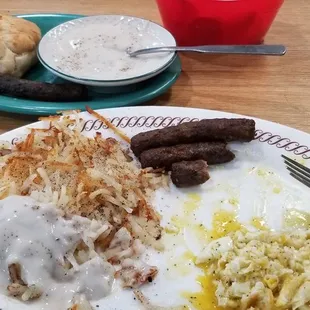 Eggs over medium with sausage and hash browns, biscuit and gravy.