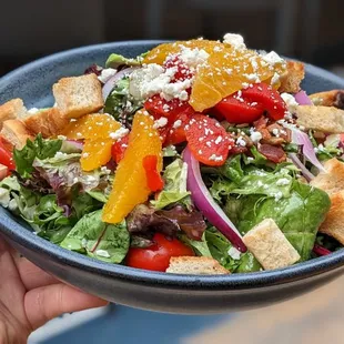 a hand holding a bowl of salad