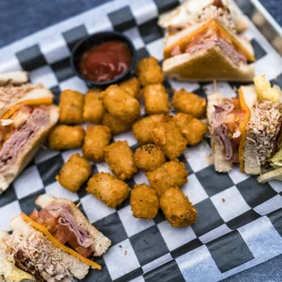 a tray of sandwiches and tater tots