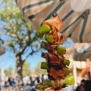 a hand holding a skewer of food