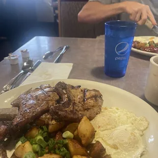 Two bone in delicious pork chops with over easy, &amp; country potatoes with onions and green peppers.