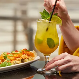 a person holding a drink and a plate of food