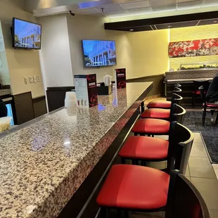a bar with red chairs and televisions