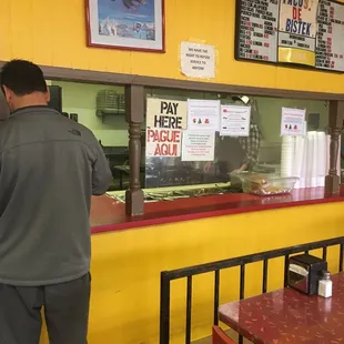 a man standing at the counter of a fast food restaurant