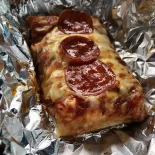 a slice of pepperoni pizza wrapped in foil