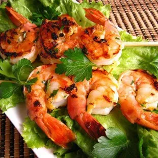 a plate of shrimp skewers on lettuce