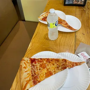 two slices of pizza on paper plates