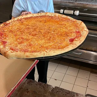 a woman holding a large pizza
