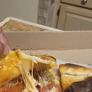 a person taking a slice of pizza