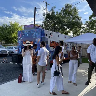 a group of people standing in front of a food truck