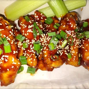 a plate of chicken wings with sesame seeds and celery
