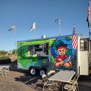 a table and chairs outside of a food truck