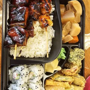 a bento tray with rice, meat, and vegetables