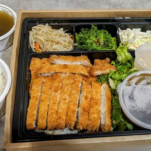 a bento lunch with rice, salad, and soup